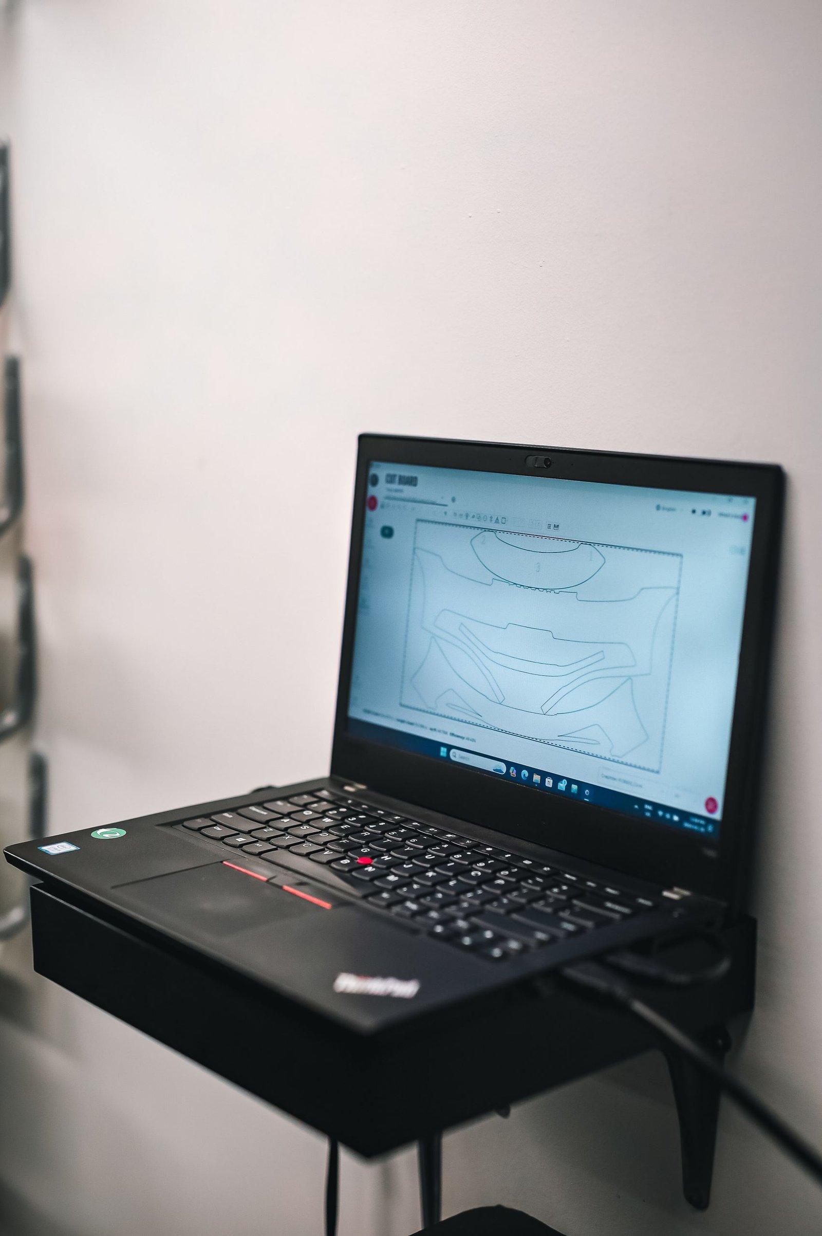 Laptop screen showing a technical drawing placed on a wall-mounted shelf with a white background.