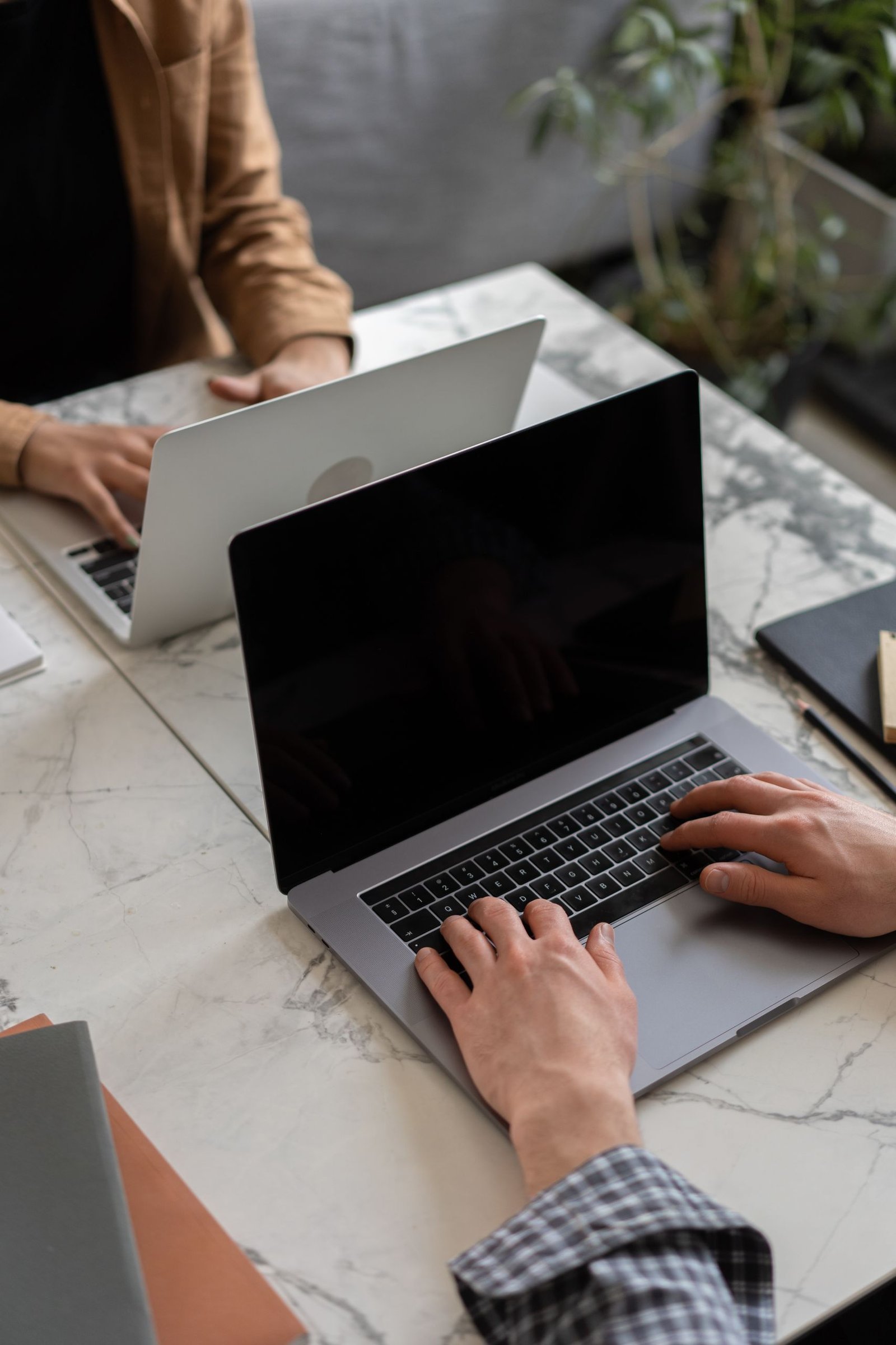Two people working on laptops in a modern office setting, showcasing teamwork and productivity.